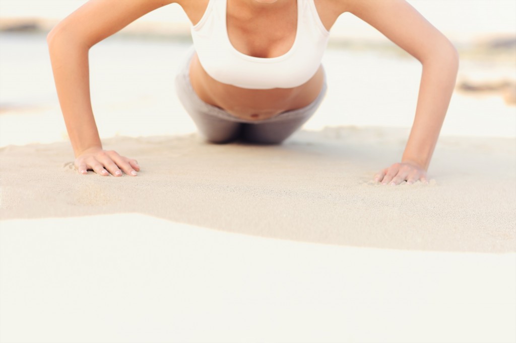 Woman doing push-ups at the beach